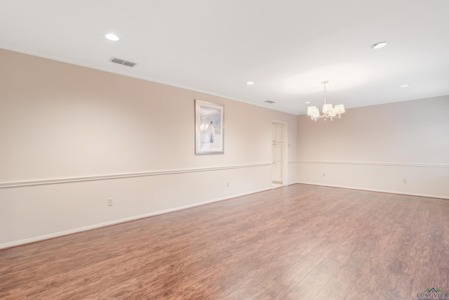 empty room with hardwood / wood-style flooring and an inviting chandelier