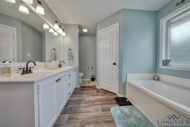 846 Edgewood Cir, Lindale, TX 75771 - bathroom featuring double vanity, a garden tub, wood finished floors, and toilet