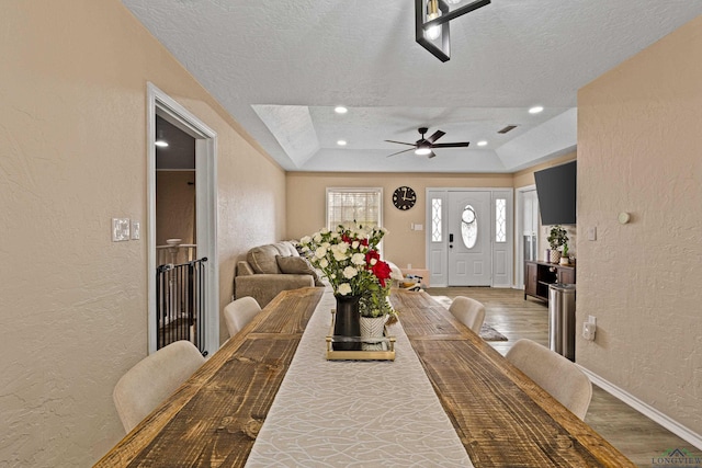 dining space with hardwood / wood-style flooring, a raised ceiling, and a textured ceiling