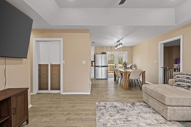 living room with french doors, ceiling fan, a textured ceiling, and light hardwood / wood-style flooring