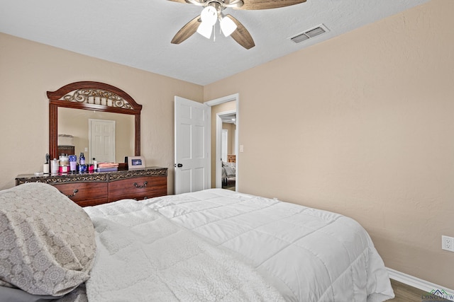 bedroom with hardwood / wood-style flooring, a textured ceiling, and ceiling fan