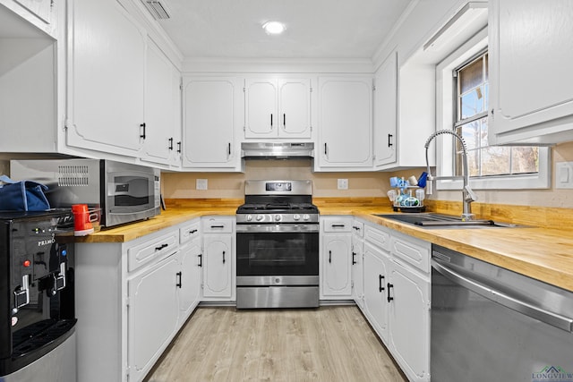 kitchen with stainless steel appliances, white cabinetry, sink, and light hardwood / wood-style flooring