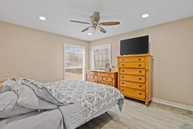 bedroom featuring ceiling fan, a textured ceiling, and light hardwood / wood-style floors