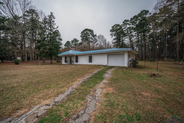 single story home with driveway, metal roof, a garage, and a front lawn