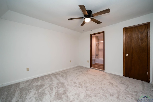 unfurnished bedroom with ensuite bath, carpet, baseboards, and a ceiling fan