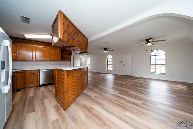 kitchen with open floor plan, light countertops, stainless steel dishwasher, light wood-type flooring, and brown cabinetry