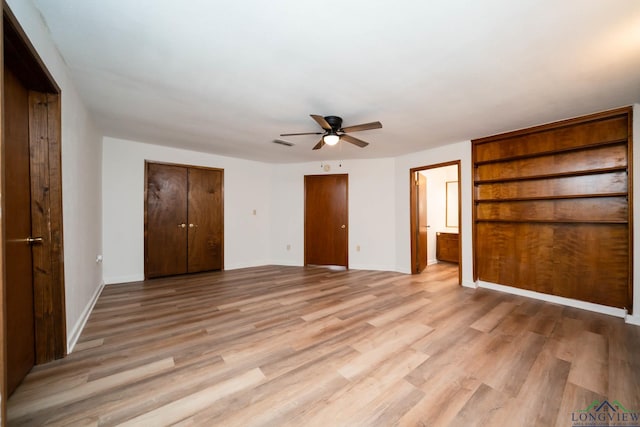 unfurnished bedroom featuring baseboards, ensuite bath, visible vents, and light wood-style floors