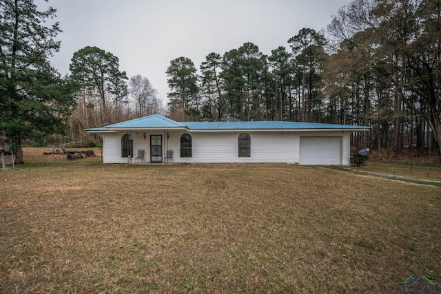 ranch-style home featuring metal roof, an attached garage, driveway, and a front lawn