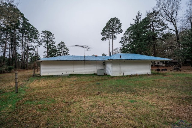 rear view of property with metal roof and a lawn