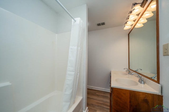 full bath featuring shower / tub combo, visible vents, a sink, and wood finished floors