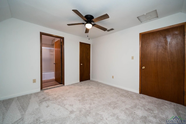 unfurnished bedroom featuring carpet floors, visible vents, vaulted ceiling, and connected bathroom