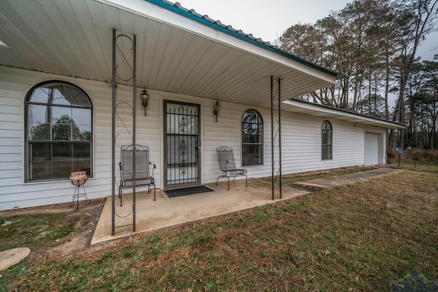 view of exterior entry with a garage and a lawn