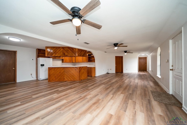 unfurnished living room featuring light wood-type flooring, arched walkways, and visible vents