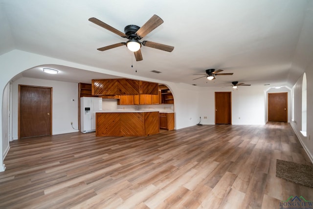 unfurnished living room with light wood-type flooring and arched walkways