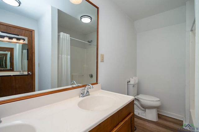 bathroom with toilet, a shower with shower curtain, wood finished floors, a sink, and double vanity