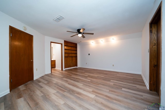 interior space featuring baseboards, visible vents, ensuite bath, ceiling fan, and light wood-type flooring