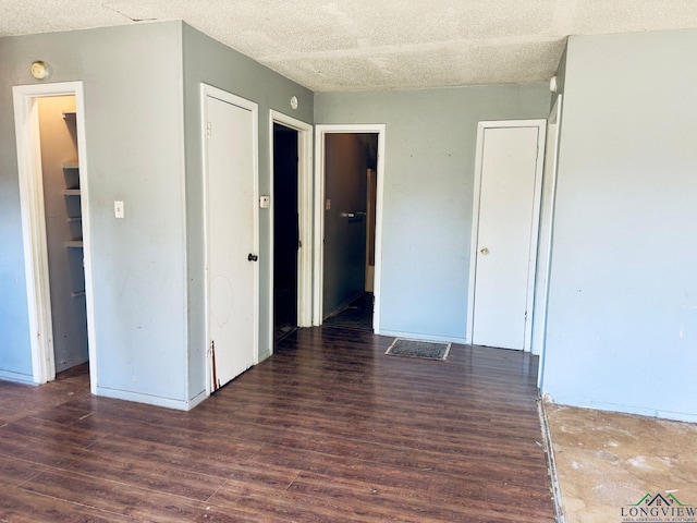 unfurnished room with a textured ceiling and dark wood-type flooring