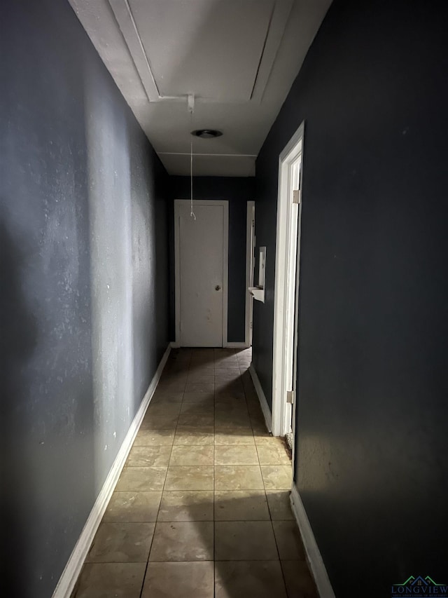 hallway featuring attic access, tile patterned flooring, and baseboards