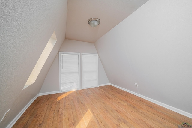 additional living space featuring vaulted ceiling, hardwood / wood-style flooring, and baseboards