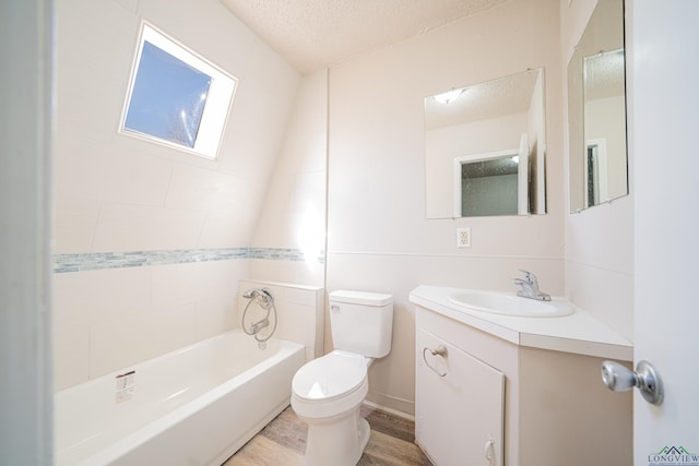 bathroom featuring toilet, vanity, wood finished floors, a textured ceiling, and shower / bathtub combination