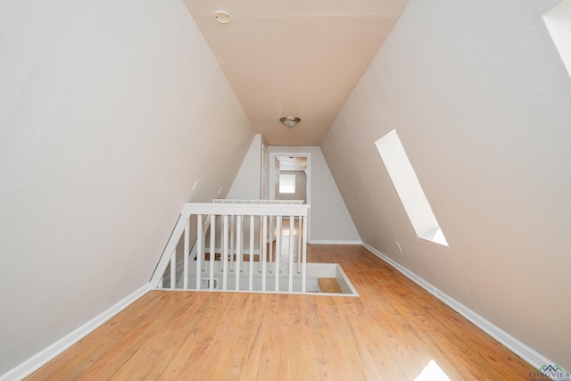 additional living space featuring lofted ceiling, baseboards, and wood finished floors