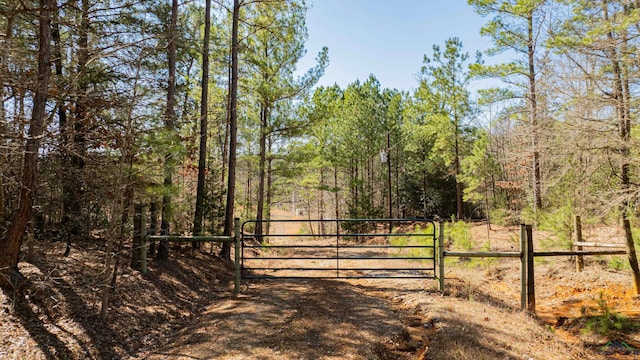 view of gate with a wooded view and fence