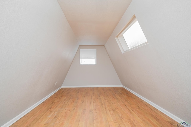 additional living space featuring lofted ceiling, baseboards, and light wood finished floors