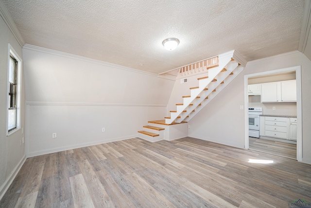 spare room featuring light wood finished floors, a textured ceiling, stairway, and crown molding