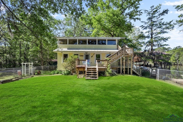 rear view of house featuring a yard, a deck, and a sunroom