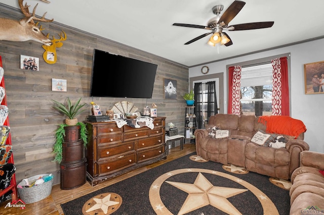 living room with hardwood / wood-style floors, wooden walls, ornamental molding, and ceiling fan