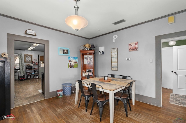 dining area with crown molding and dark wood-type flooring