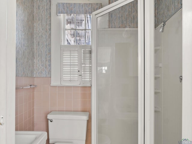 bathroom featuring a shower stall, toilet, and tile walls