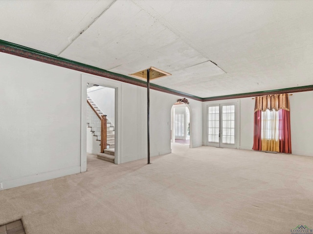 unfurnished room with arched walkways, carpet floors, ornamental molding, and stairs