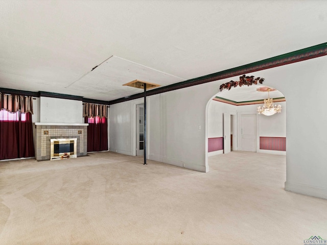 unfurnished living room with arched walkways, ornamental molding, carpet, and a fireplace