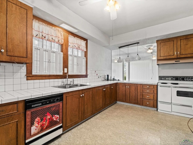 kitchen with plenty of natural light, range with two ovens, dishwasher, brown cabinets, and a sink