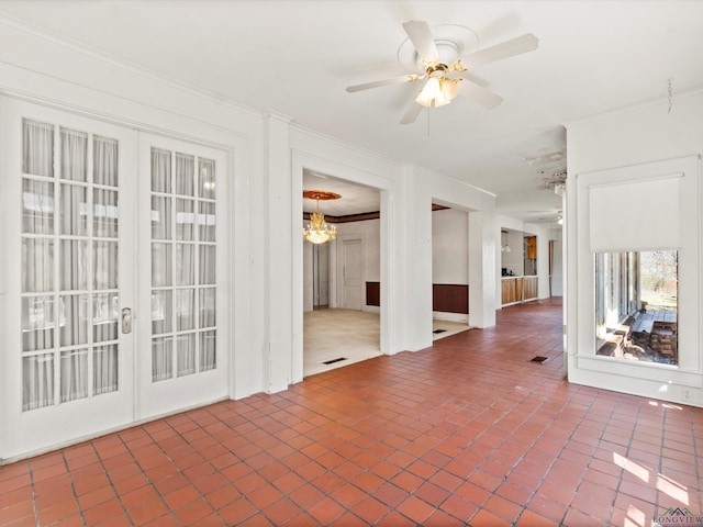 spare room with brick floor, french doors, crown molding, and ceiling fan with notable chandelier