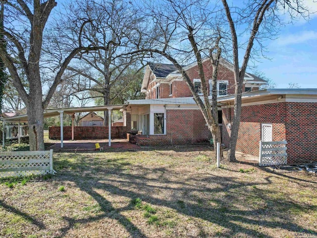 exterior space with a yard, brick siding, and fence