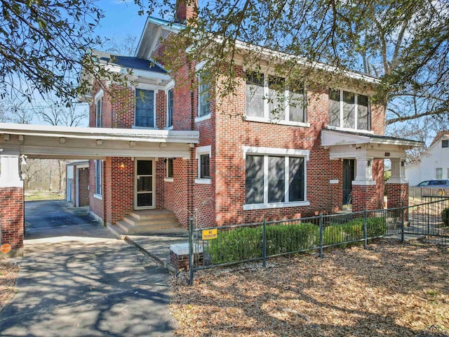 view of front of house featuring a fenced front yard, aphalt driveway, an attached carport, and brick siding