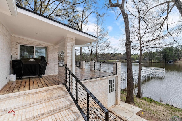 wooden terrace featuring a grill and a water view