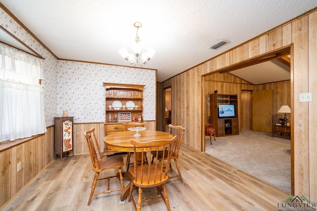 dining room with a textured ceiling, light hardwood / wood-style floors, a chandelier, and crown molding