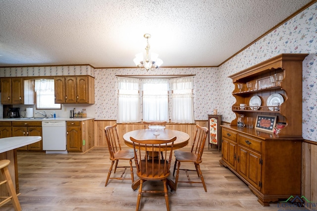 dining room featuring a notable chandelier, a textured ceiling, light wood-type flooring, sink, and ornamental molding