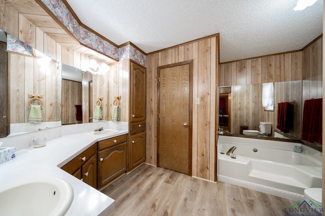 bathroom featuring wood-type flooring, toilet, a textured ceiling, vanity, and wood walls