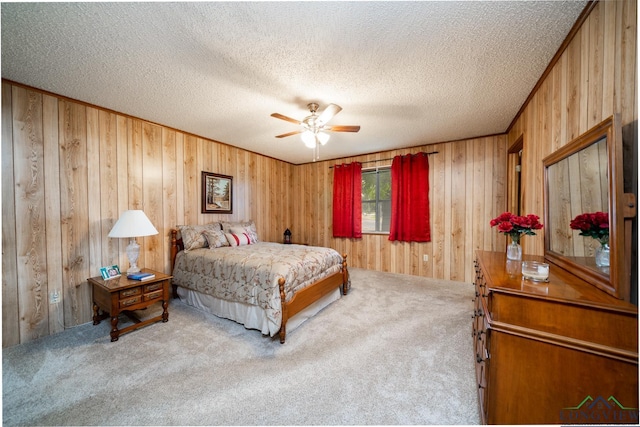 carpeted bedroom featuring ceiling fan, a textured ceiling, and wood walls