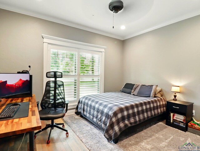 bedroom with wood finished floors and ornamental molding