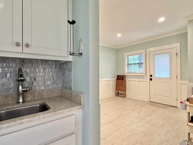 interior space with a decorative wall, crown molding, wainscoting, and a sink