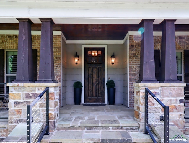 entrance to property featuring covered porch and brick siding