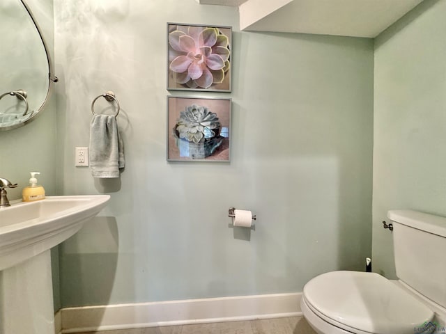 bathroom featuring baseboards, toilet, and a sink