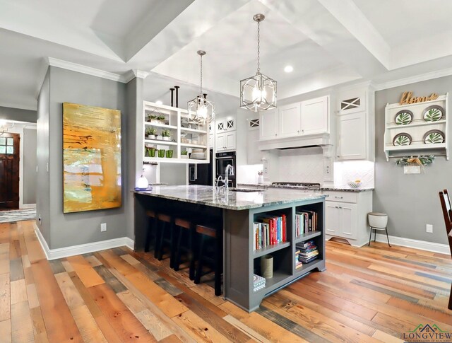 kitchen with light stone countertops, open shelves, white cabinets, backsplash, and a notable chandelier