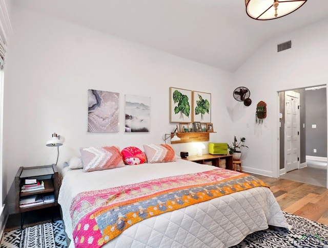 bedroom featuring lofted ceiling, wood finished floors, visible vents, and baseboards