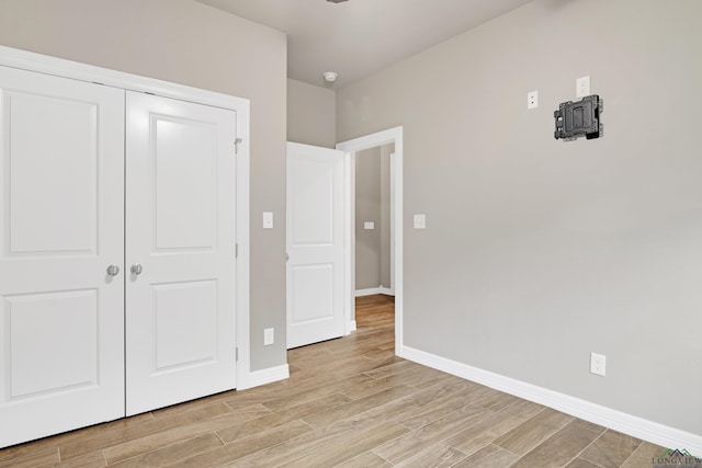 unfurnished bedroom with a closet and light wood-type flooring